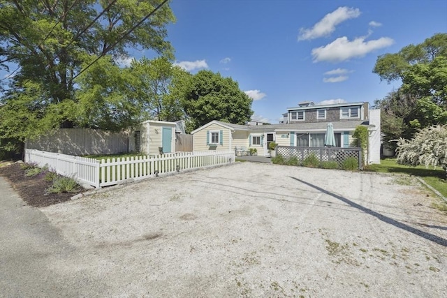 view of front facade featuring an outdoor structure, a fenced front yard, a shed, and driveway