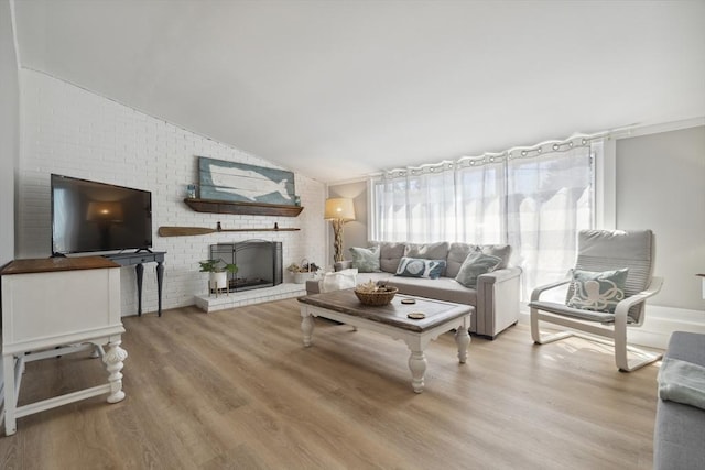 living area featuring vaulted ceiling, wood finished floors, and a fireplace