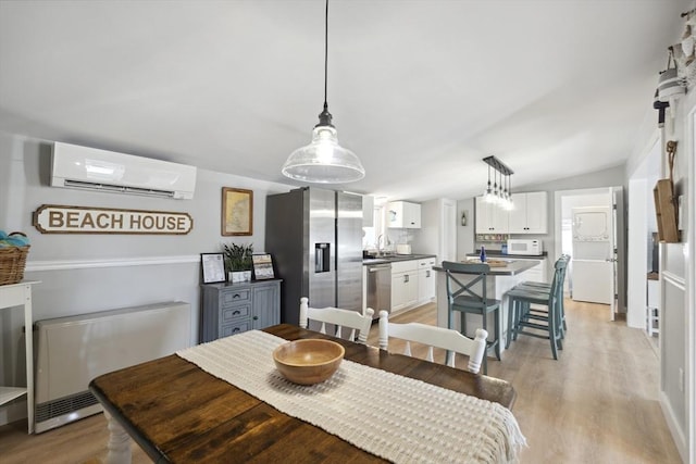 dining room featuring light wood-style floors, vaulted ceiling, and a wall mounted air conditioner