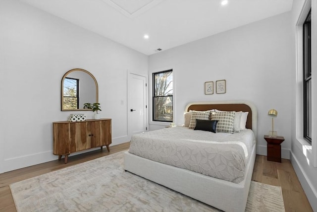 bedroom with multiple windows and hardwood / wood-style floors