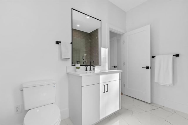 bathroom with a tile shower, vanity, and toilet