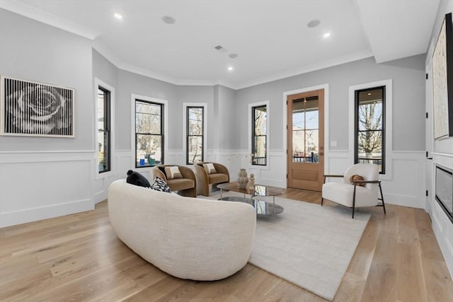 living room with a wealth of natural light, light hardwood / wood-style floors, and crown molding