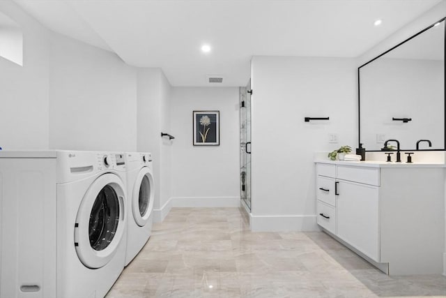 clothes washing area with washer and dryer, sink, and cabinets