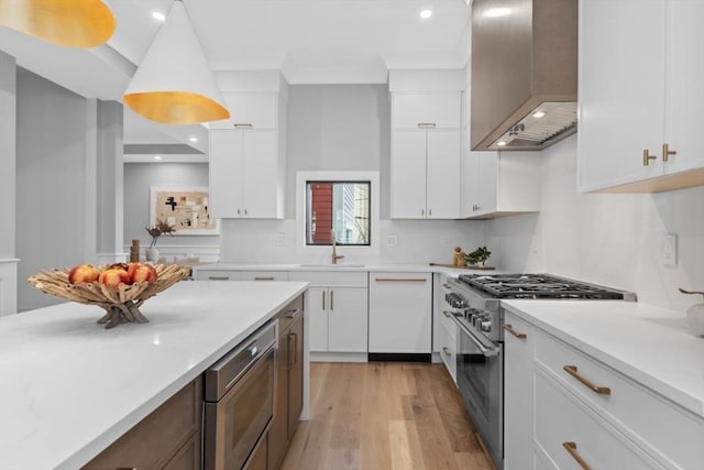 kitchen featuring high end range, light hardwood / wood-style floors, wall chimney range hood, white cabinetry, and white dishwasher