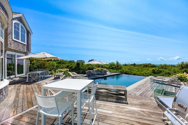 31 Moss Rd, Yarmouth, MA 02673 - view of swimming pool featuring a wooden deck, an infinity pool, and outdoor dining space