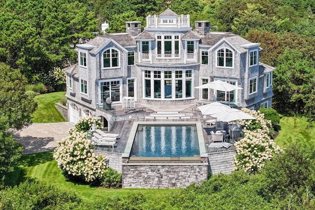 31 Moss Rd, Yarmouth, MA 02673 - rear view of house with an outdoor pool, a balcony, a wooded view, and a garage