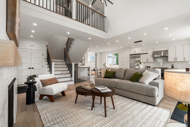 living room featuring a tile fireplace, a towering ceiling, and light wood-type flooring