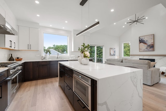 kitchen featuring appliances with stainless steel finishes, light wood-type flooring, white cabinetry, and a wealth of natural light