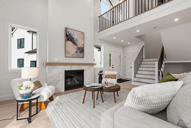 living room featuring a wealth of natural light, a fireplace, a towering ceiling, and light hardwood / wood-style flooring