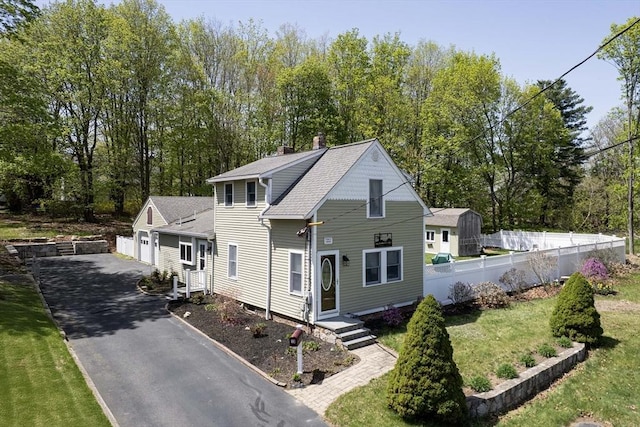 view of front of house featuring a garage, a front lawn, fence, a chimney, and driveway