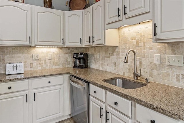 kitchen featuring a sink, decorative backsplash, white cabinets, and stainless steel dishwasher