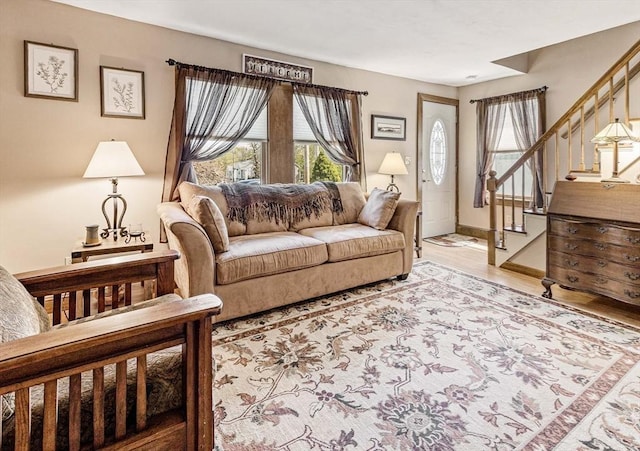 living room featuring baseboards, stairway, and light wood-style floors