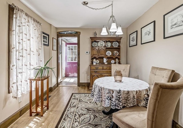 dining room with baseboards, a chandelier, and light wood-type flooring