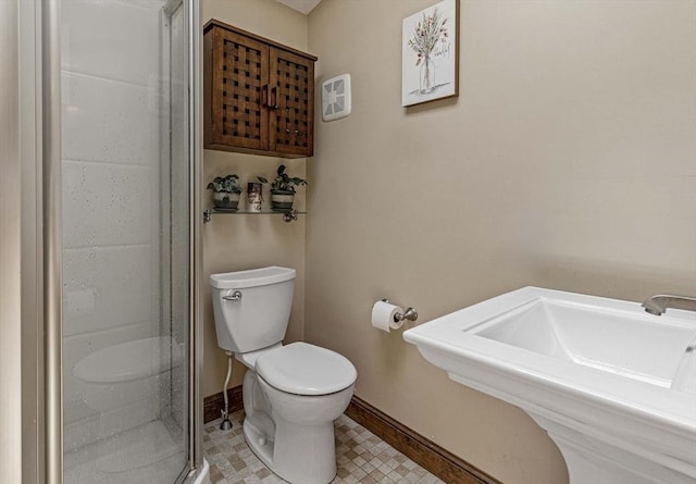 bathroom featuring baseboards, a sink, toilet, and a shower stall