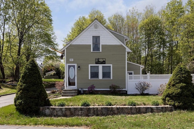 rear view of property with a lawn, fence, and entry steps