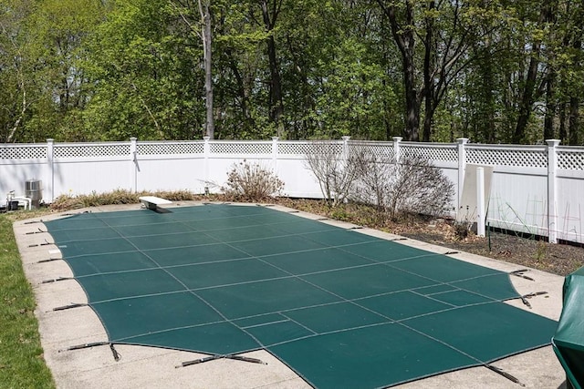 view of swimming pool featuring a fenced backyard, a fenced in pool, and a diving board