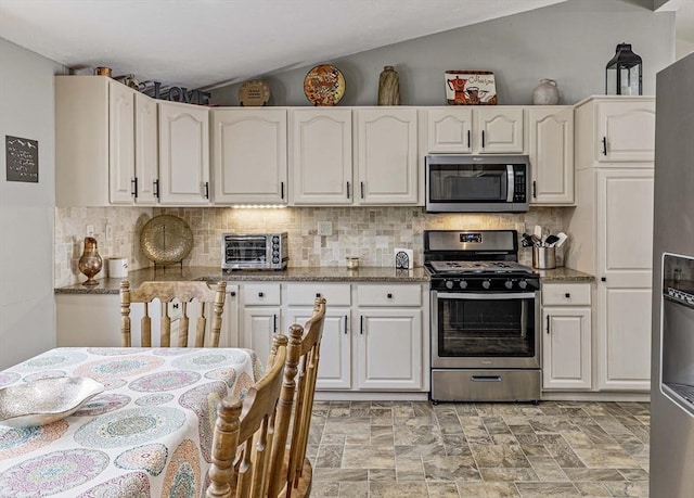 kitchen featuring vaulted ceiling, tasteful backsplash, stainless steel appliances, and white cabinetry