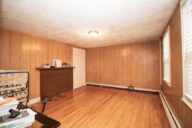 33 Cady St, Lowell, MA 01852 - office area featuring baseboard heating, wood finished floors, wooden walls, a textured ceiling, and baseboards