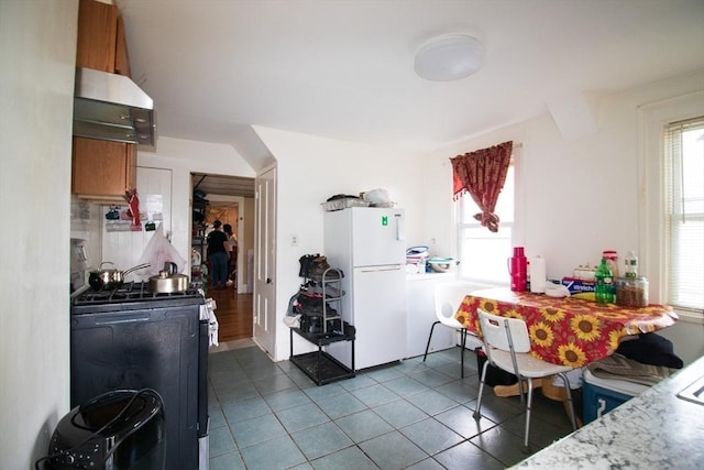 33 Cady St, Lowell, MA 01852 - kitchen featuring freestanding refrigerator, gas stove, dark tile patterned flooring, extractor fan, and brown cabinetry