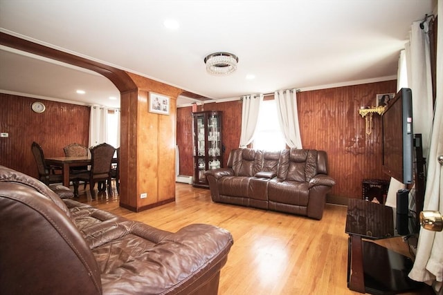 33 Cady St, Lowell, MA 01852 - living area featuring light wood finished floors, a baseboard heating unit, arched walkways, and wood walls