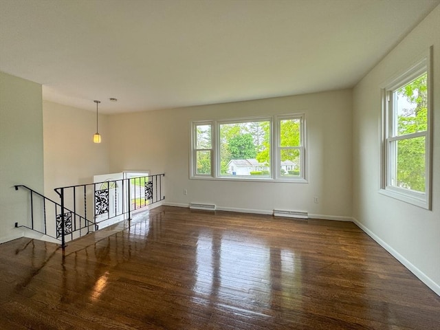 empty room with wood finished floors, baseboard heating, and baseboards