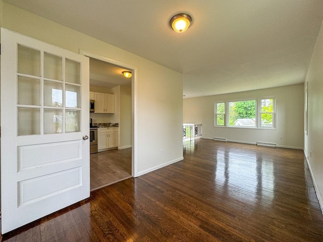 spare room with dark wood-style floors, baseboards, and baseboard heating