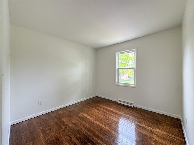 spare room with dark wood finished floors, baseboards, and baseboard heating