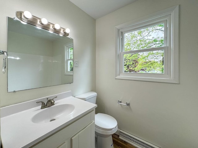 bathroom with toilet, vanity, a baseboard heating unit, and wood finished floors