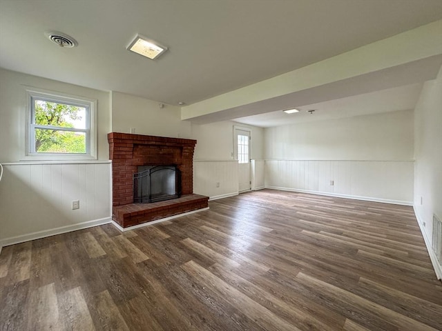 unfurnished living room featuring wood finished floors, a fireplace, wainscoting, and baseboards
