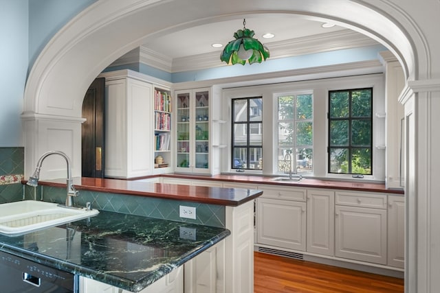 kitchen featuring sink, white cabinetry, black dishwasher, light hardwood / wood-style floors, and decorative backsplash