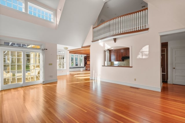 unfurnished living room featuring high vaulted ceiling and light hardwood / wood-style flooring