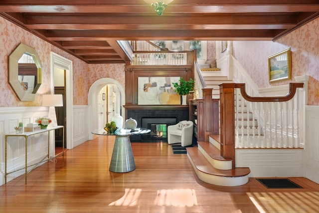 interior space with wood-type flooring, beamed ceiling, and a tiled fireplace