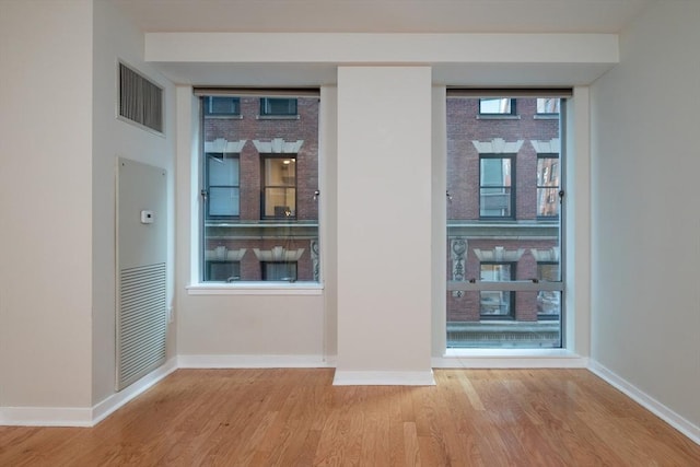 empty room with visible vents, floor to ceiling windows, baseboards, and wood finished floors