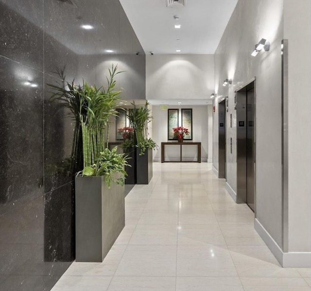 corridor featuring light tile patterned floors, visible vents, and elevator