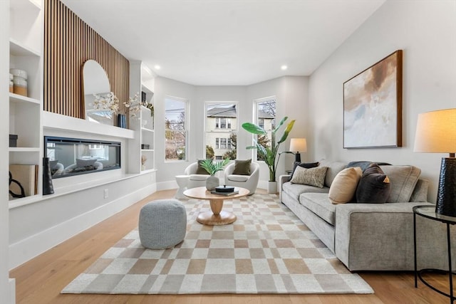 living room featuring built in shelves and light hardwood / wood-style floors