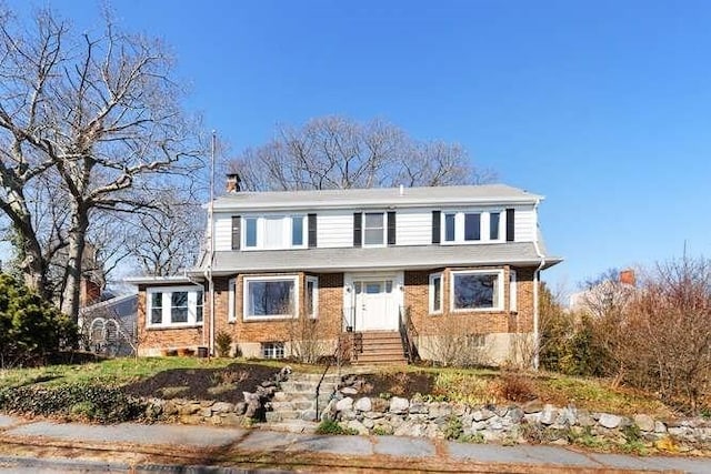 view of front of property with a chimney, brick siding, and entry steps