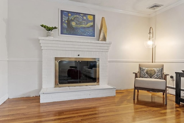 living area with crown molding, a fireplace, and hardwood / wood-style floors