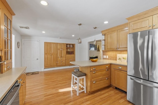 kitchen with pendant lighting, black dishwasher, stainless steel fridge, a kitchen bar, and backsplash