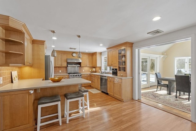 kitchen with stainless steel appliances, a breakfast bar, a wealth of natural light, and kitchen peninsula