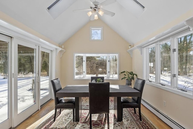 dining area with baseboard heating, a healthy amount of sunlight, vaulted ceiling, and light wood-type flooring