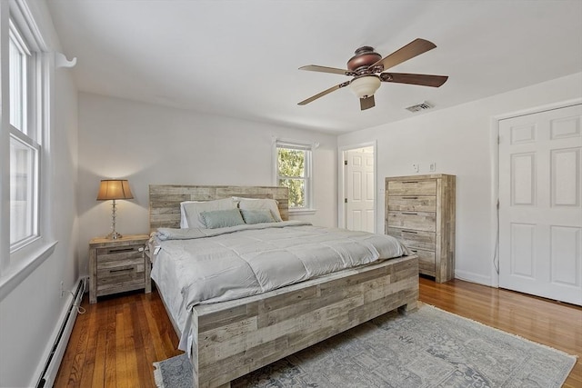 bedroom featuring dark hardwood / wood-style flooring, a baseboard radiator, and ceiling fan