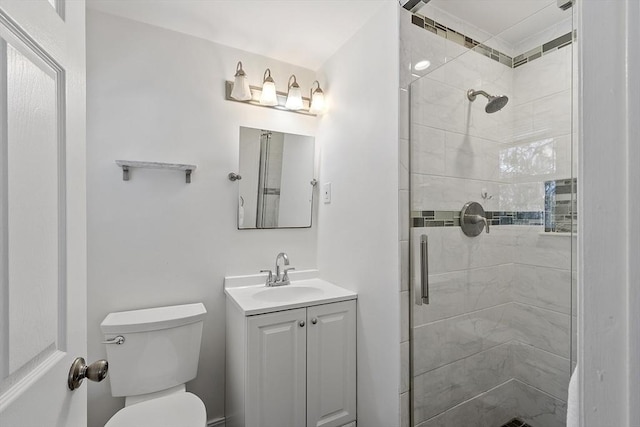 bathroom with toilet, vanity, and a shower with shower door