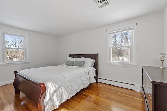 bedroom with baseboard heating and wood-type flooring