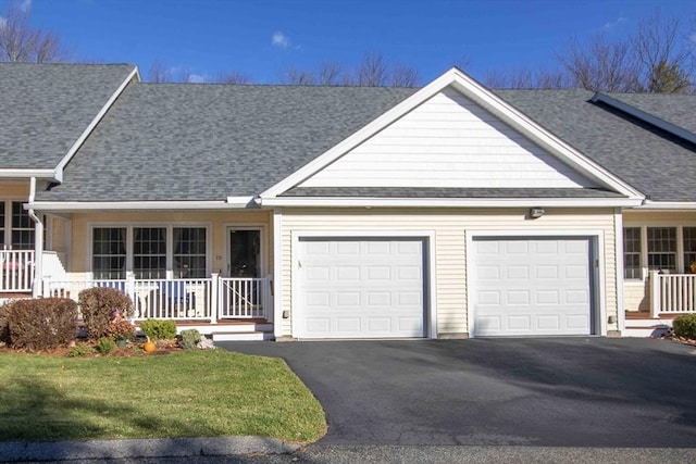 ranch-style home featuring an attached garage, covered porch, driveway, and roof with shingles