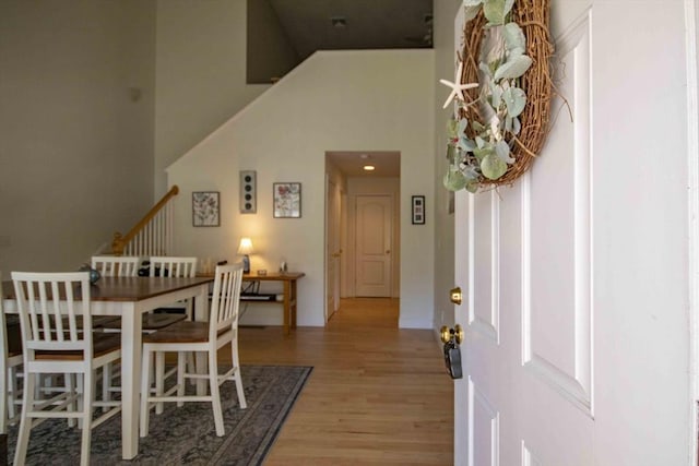 dining room with light wood finished floors, stairway, and a high ceiling