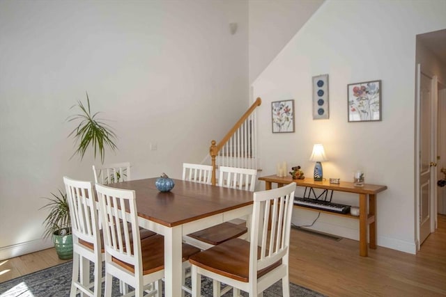 dining area featuring stairs, baseboards, and wood finished floors