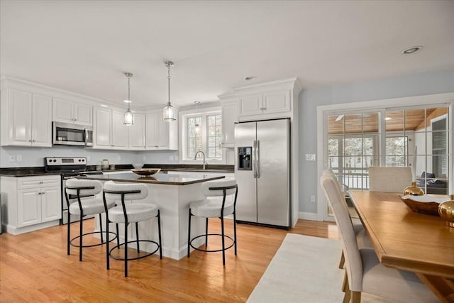 kitchen featuring white cabinets, dark countertops, a breakfast bar, a center island, and stainless steel appliances