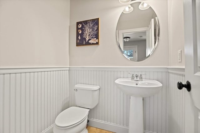 bathroom with wainscoting, a sink, and toilet