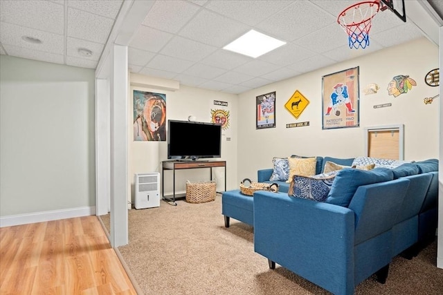 living area featuring a paneled ceiling, baseboards, and wood finished floors