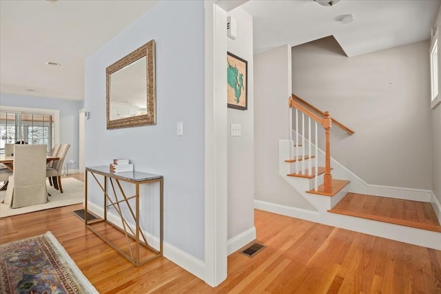 interior space featuring stairway, light wood-style flooring, visible vents, and baseboards